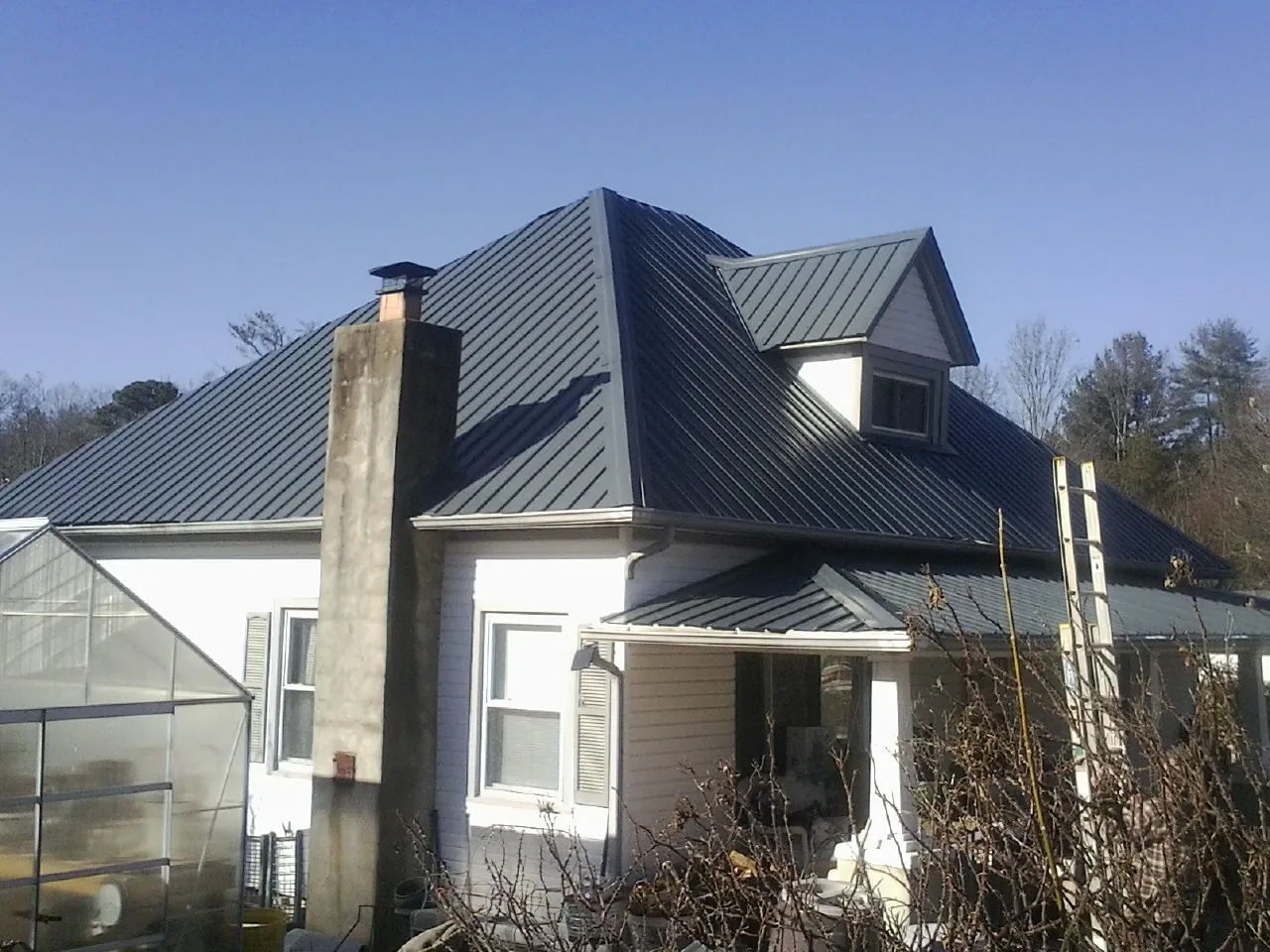 Dark blue standing seam metal roof on a white farmhouse with dormer — Slate & Tile Roof Repair by Roofing Brothers in Kensington